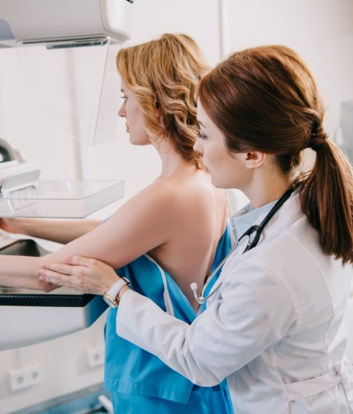 attentive radiologist preparing woman for mammography test on x-ray machine